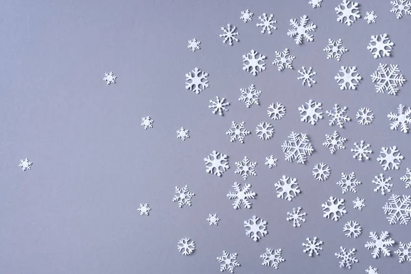 Patrón de invierno hecho de copos de nieve blancos sobre fondo gris. Vista superior. Acostado. Composición de invierno. Navidad, concepto de año nuevo. — Foto de Stock