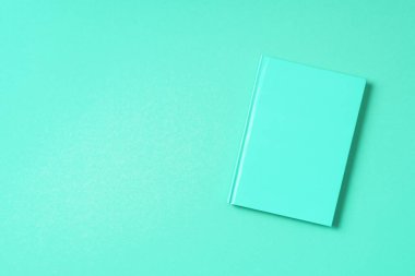 Modayı takip eden yeşil arka planda kapalı bir defter. Üst görünüm, boşluğu kopyala. Kadın işleri, ders çalışmak, okul konseptine geri dönmek. Zaman çizelgesi, yapılacak listeler