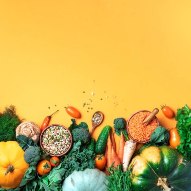 Vegan ve vejetaryen diyeti, hasat konsepti. Sonbahar sebzeleri, mercimek, fasulye, sarı arka planda yemek pişirmek için ham malzemeler. Sağlıklı, temiz yeme konsepti. Uzayı kopyala Üst görünüm.