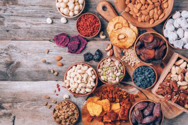 Fındık ve kurutulmuş meyve çeşitleri - Brezilya cevizi, kaju, ceviz, badem, macadamia, çam fıstığı, fındık, ananas, kuru kayısı, goji, papaya, incir, ahşap zemin üzerinde dut