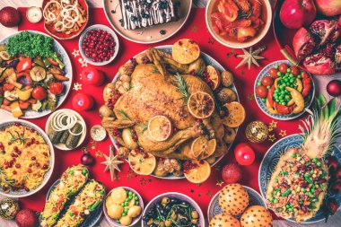 Kızarmış Noel tavuğu, portakal dilimleri, kızılcık, sarımsak, şenlikli dekorasyon, mumlar, mandalina, nar, altın külçeler, yıldız pırıltısı. Şenlikli aile Noel yemeği.