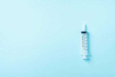Mavi arka planda şırınga ve iğne. Enjeksiyon ve aşı konsepti. Karantina Coronavirus salgını sırasında sağlık ekipmanları