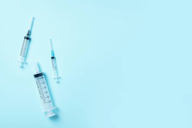 Mavi arka planda farklı boyutlarda şırıngalar. Enjeksiyon ve aşı konsepti. Koronavirüs salgını sırasında sağlık koruma ekipmanları. Üst Manzara. Boşluğu kopyala
