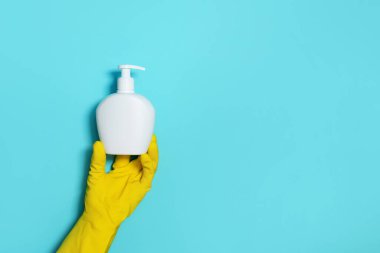 Mavi arka planda sabun şişesi ve tıbbi maske tutan eldiven. Uzayı kopyala Koronavirüse karşı koruyucu önlemler. Salgın sırasında güvenli kalacak ürünler. Covid19 karantina sırasında..