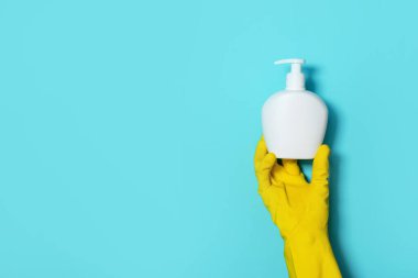 Mavi arka planda sabun şişesi ve tıbbi maske tutan eldiven. Uzayı kopyala Koronavirüse karşı koruyucu önlemler. Salgın sırasında güvenli kalacak ürünler. Covid19 karantina sırasında..