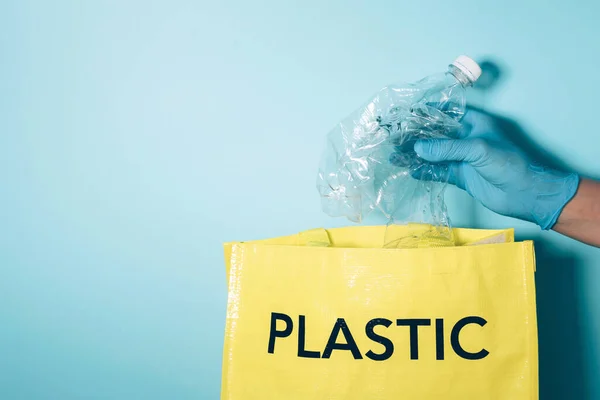 Tangan dengan sarung tangan biru menempatkan botol plastik di tempat sampah daur ulang. Perawatan lingkungan, penyortiran limbah. Salin ruang. Kehidupan normal baru setelah pandemi karantina coronavirus. Daur ulang, nol limbah, konsep ekologi. — Stok Foto