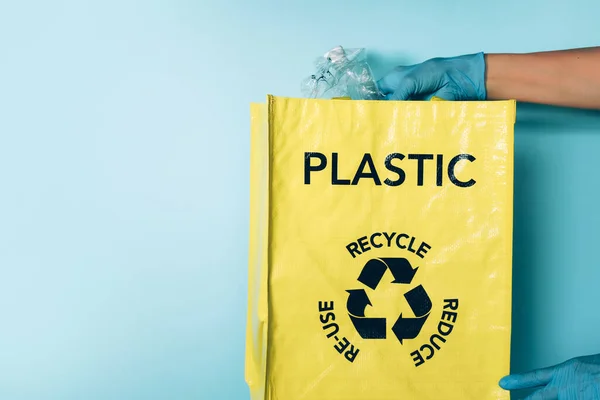 Tangan dengan sarung tangan biru menempatkan botol plastik di tempat sampah daur ulang. Perawatan lingkungan, penyortiran limbah. Salin ruang. Kehidupan normal baru setelah pandemi karantina coronavirus. Daur ulang, nol limbah, konsep ekologi. — Stok Foto