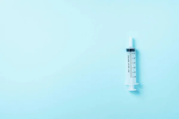 Jeringa y aguja sobre fondo azul. Inyecciones y concepto de vacunación. Equipos de protección sanitaria durante la pandemia del Coronavirus en cuarentena —  Fotos de Stock