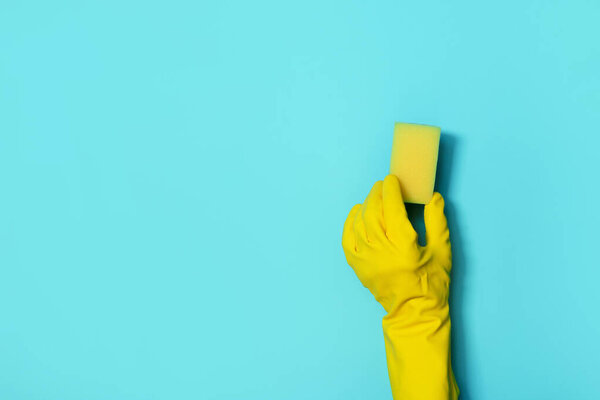 Hand in glove holding microfiber cleaning cloth, sponge on blue background. Copy space. Cleaning service concept. Spring general or regular clean up. Commercial cleaning company concept.