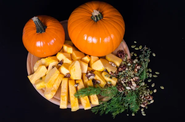 Two pumpkins and slices with herbs, seeds — Stock Photo, Image