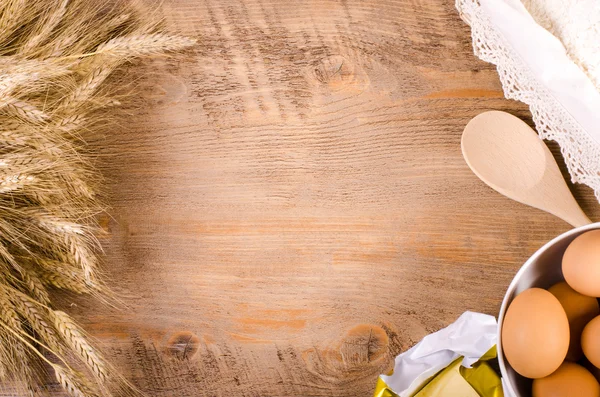 Baking background with ears of wheat, flour, eggs and butter — Stock Photo, Image