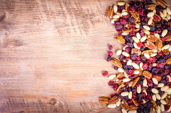 Dried fruits - pecan, cranberry, raisin, almond on wooden background. Free space for text. — Stock Photo, Image