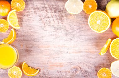 Bir closeup dilimlenmiş portakal ve ahşap zemin üzerine taze portakal suyu yığını. Çerçeve yeme. Metin için boş alan