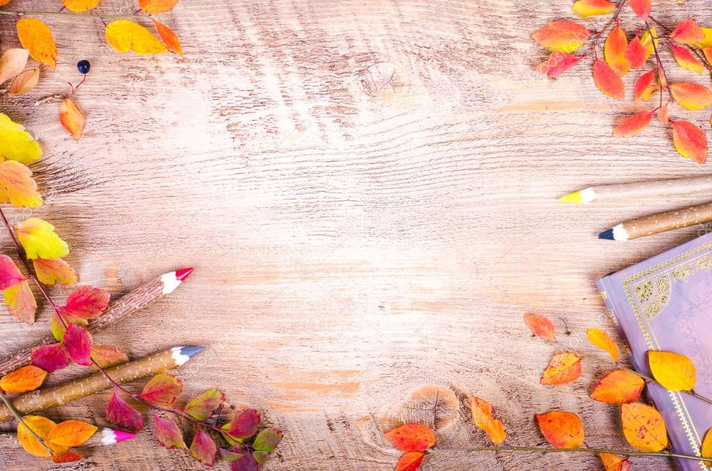 Autumn leaves, notebook, diary, pencils lying over wooden background with copy space. Fall and thanksgiving setting. Autumn composition.