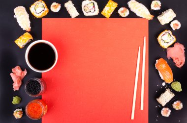 Sushi set, soy sauce, ginger, wasabi on black and red background