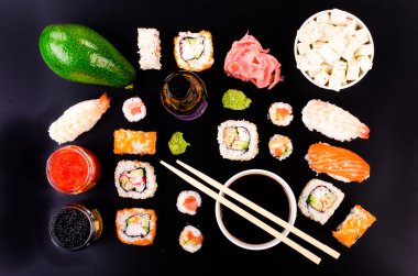 Sushi set, soy cheese, lime, avocado, ginger, red caviar, black caviar,  soy sauce, wasabi on black background