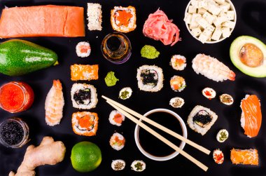Sushi set, soy cheese, lime, avocado, ginger, red caviar, black caviar,  soy sauce, wasabi on black background. Food background
