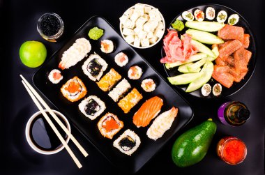 Sushi set, soy cheese, lime, avocado, ginger, red caviar, black caviar,  soy sauce, wasabi on black background