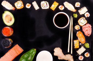 Sushi set, soy sauce, ginger, wasabi on black background. Free space for your text. Food frame