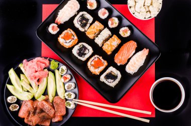 Suşi seti, soya sosu, zencefil, wasabi, siyah ve kırmızı karaca, avokado, somon, siyah ve kırmızı arka plan peynir. 