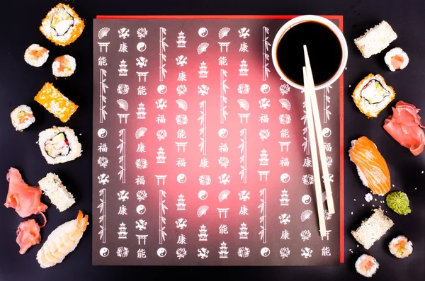 Sushi set, soy sauce, ginger, wasabi on black background with Japanese characters — Stock fotografie