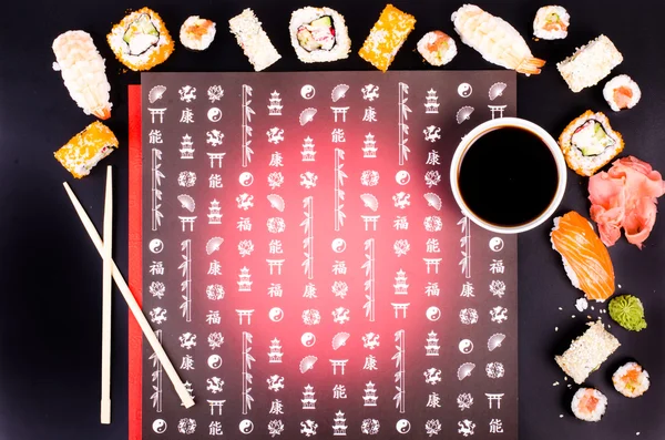 Sushi set, soy sauce, ginger, wasabi on black background with Japanese characters — Stock fotografie