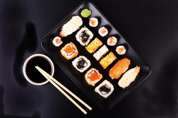 Sushi set served on a plate, soy cheese, lime on black background — Stock fotografie