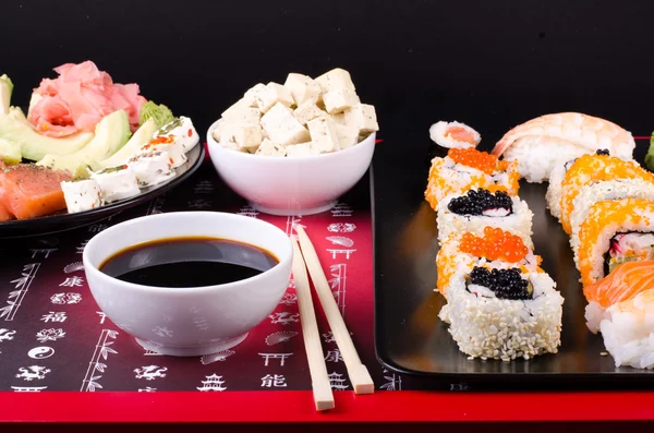 Sushi set served on a plate, soy cheese, lime on black background — ストック写真