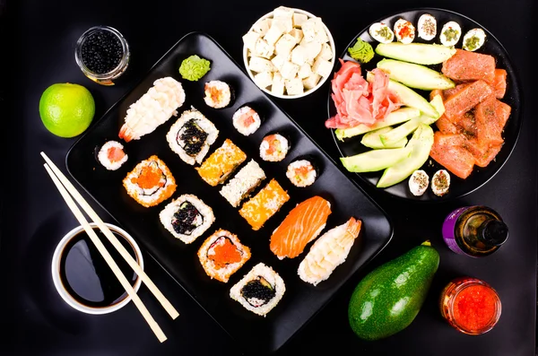 Sushi set, soy cheese, lime, avocado, ginger, red caviar, black caviar,  soy sauce, wasabi on black background — ストック写真