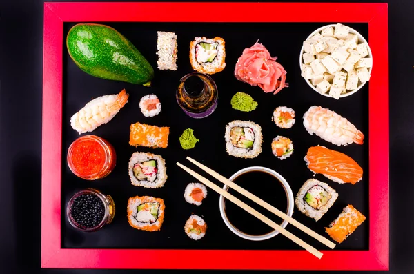 Set de sushi, queso de soja, lima, jengibre, aguacate, caviar rojo, caviar negro, salsa de soja, wasabi sobre fondo negro con marco rojo —  Fotos de Stock