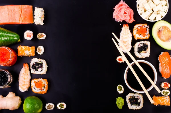Sushi set, soy sauce, ginger, wasabi on black background. Free space for your text. Food frame