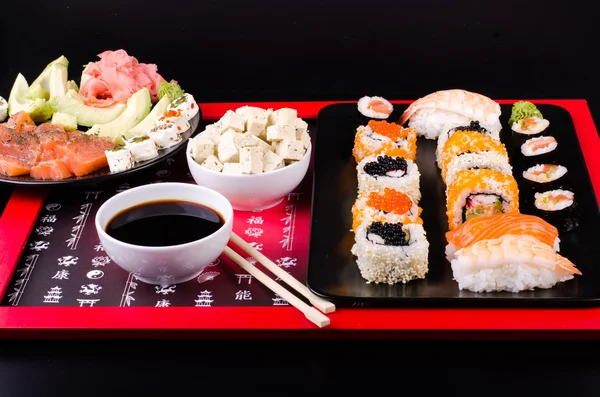 Sushi set served on a plate, soy cheese, lime on black background — Stock fotografie