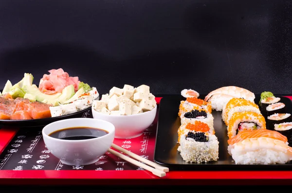 Sushi set served on a plate, soy cheese, lime on black background — Stock fotografie