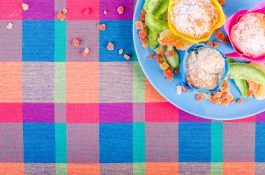 Fresh homemade muffins with dried fruits on a colorful checkered kitchen towel. Free space for your text
