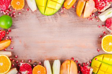 Fresh fruits on a wooden background. Raw and vegetarian eating frame. Sliced orange, persimmon, kiwi, tangerine, banana, lemon, apple,  grapefruit, pomegranate, lime, mango. Fruit set.