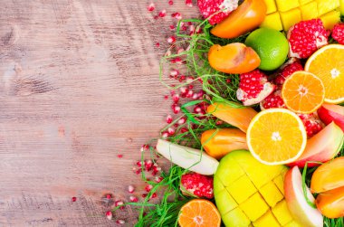 Fresh fruits on grass and wooden background. Raw and vegetarian eating frame. Sliced orange, persimmon, kiwi, tangerine, banana, lemon, apple,  grapefruit, pomegranate, lime, mango. Fruit set.