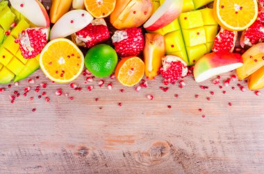 Fresh fruits on a wooden background. Raw and vegetarian eating frame. Sliced orange, persimmon, kiwi, tangerine, banana, lemon, apple,  grapefruit, pomegranate, lime, mango. Fruit set.