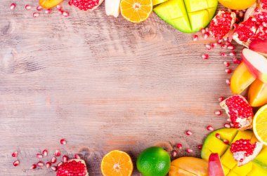 Fresh fruits on a wooden background. Raw and vegetarian eating frame. Sliced orange, persimmon, kiwi, tangerine, banana, lemon, apple,  grapefruit, pomegranate, lime, mango. Fruit set.