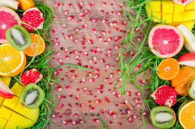 Fresh fruits on grass and wooden background. Raw and vegetarian eating frame. Sliced orange, persimmon, kiwi, tangerine, banana, lemon, apple,  grapefruit, pomegranate, lime, mango. Fruit set.