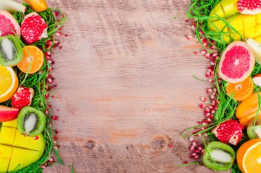 Fresh fruits on grass and wooden background. Raw and vegetarian eating frame. Sliced orange, persimmon, kiwi, tangerine, banana, lemon, apple,  grapefruit, pomegranate, lime, mango. Fruit set.