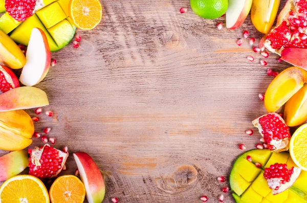 Frutas frescas sobre un fondo de madera. Marco alimenticio crudo y vegetariano. Naranja en rodajas, caqui, kiwi, mandarina, plátano, limón, manzana, pomelo, granada, lima, mango. Conjunto de frutas . —  Fotos de Stock