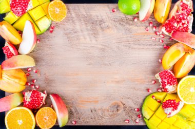 Fresh fruits on a wooden background. Raw and vegetarian eating frame. Sliced orange, persimmon, kiwi, tangerine, banana, lemon, apple,  grapefruit, pomegranate, lime, mango. Fruit set.