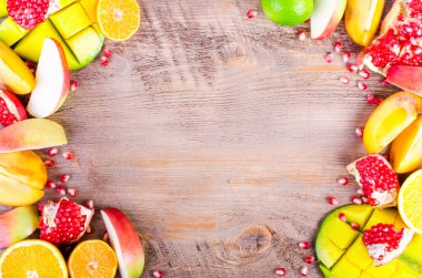 Fresh fruits on a wooden background. Raw and vegetarian eating frame. Sliced orange, persimmon, kiwi, tangerine, banana, lemon, apple,  grapefruit, pomegranate, lime, mango. Fruit set.