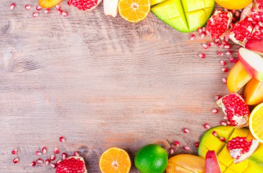 Fresh fruits on a wooden background. Raw and vegetarian eating frame. Sliced orange, persimmon, kiwi, tangerine, banana, lemon, apple,  grapefruit, pomegranate, lime, mango. Fruit set.