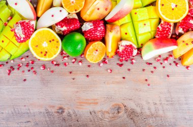 Fresh fruits on a wooden background. Raw and vegetarian eating frame. Sliced orange, persimmon, kiwi, tangerine, banana, lemon, apple,  grapefruit, pomegranate, lime, mango. Fruit set.