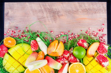 Fresh fruits on a wooden background. Raw and vegetarian eating frame. Sliced orange, persimmon, kiwi, tangerine, banana, lemon, apple,  grapefruit, pomegranate, lime, mango. Fruit set.
