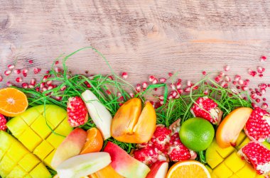Fresh fruits on a wooden background. Raw and vegetarian eating frame. Sliced orange, persimmon, kiwi, tangerine, banana, lemon, apple,  grapefruit, pomegranate, lime, mango. Fruit set.