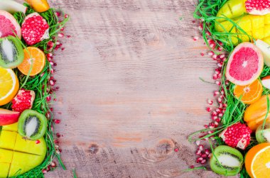 Fresh fruits on grass and wooden background. Raw and vegetarian eating frame. Sliced orange, persimmon, kiwi, tangerine, banana, lemon, apple,  grapefruit, pomegranate, lime, mango. Fruit set.
