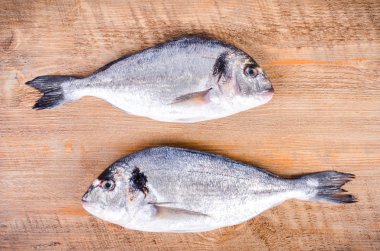 Fresh raw gilthead fishes on wooden background. Healthy food concept. Food frame.