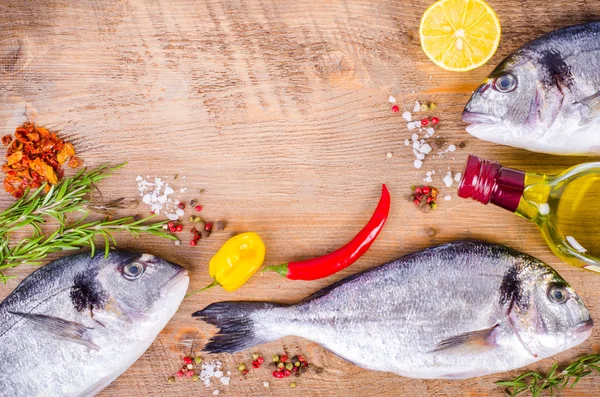Peixes gilthead crus frescos com limão, ervas, azeite, sal sobre fundo de madeira. Conceito de alimentação saudável. Quadro alimentar — Fotografia de Stock